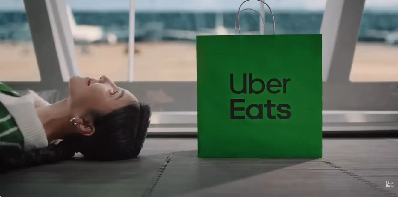 楊謹華躺在機場的行人輸送帶。（圖／翻攝自Uber Eats YouTube）